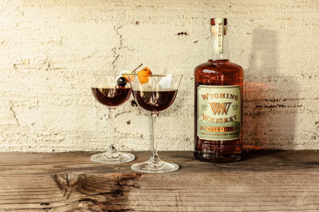 bottle of whiskey and two cocktails on a table