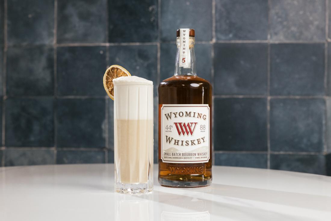 bottle of whiskey next to a tall cocktail glass