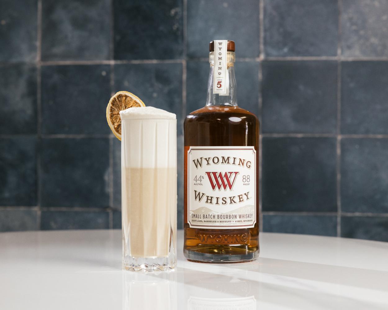 bottle of whiskey next to a tall cocktail glass