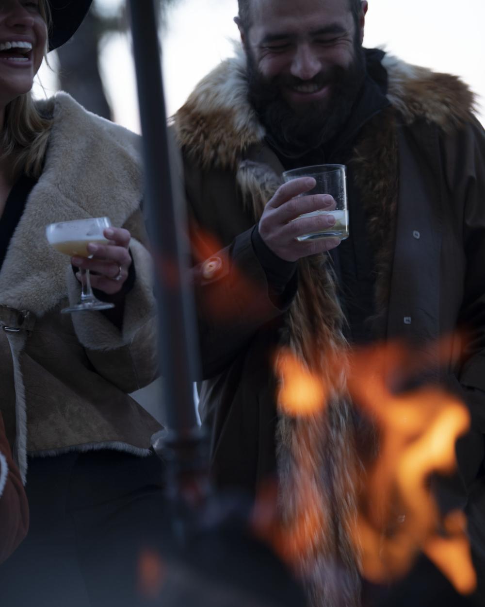 Whiskey glasses in front of fire, with man in background