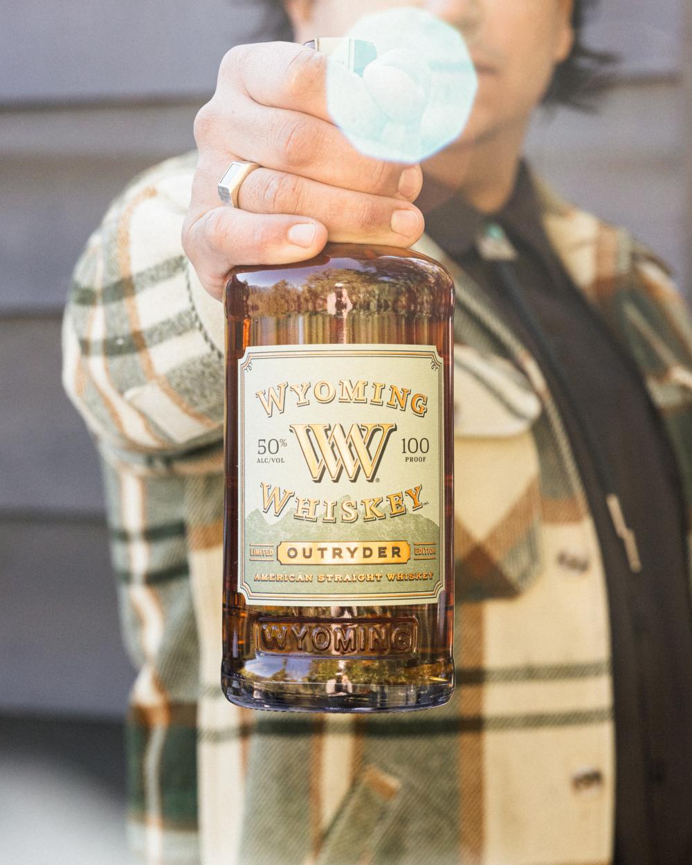 man holding out a bottle of whiskey