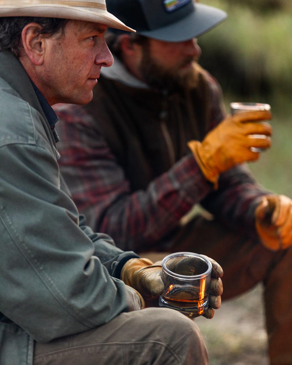 two men sitting around with glasses of whiskey