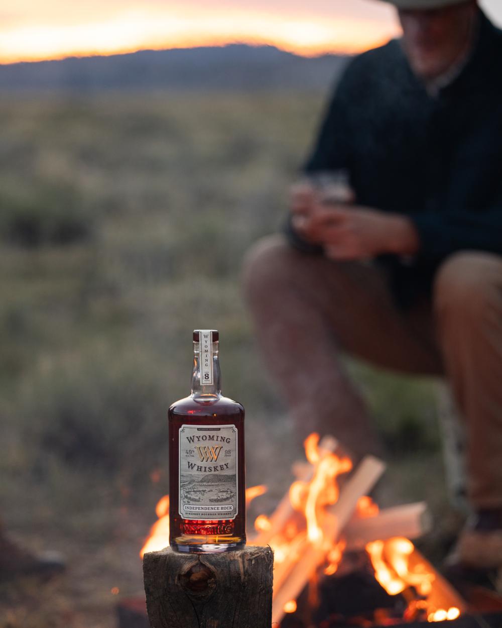 whiskey in front of a fire with a man in the background