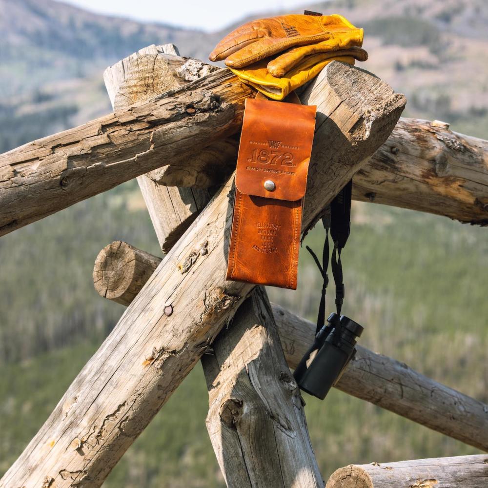 Leather bottle case hanging from a wooden fence