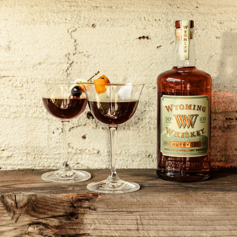 bottle of whiskey and two cocktails on a table