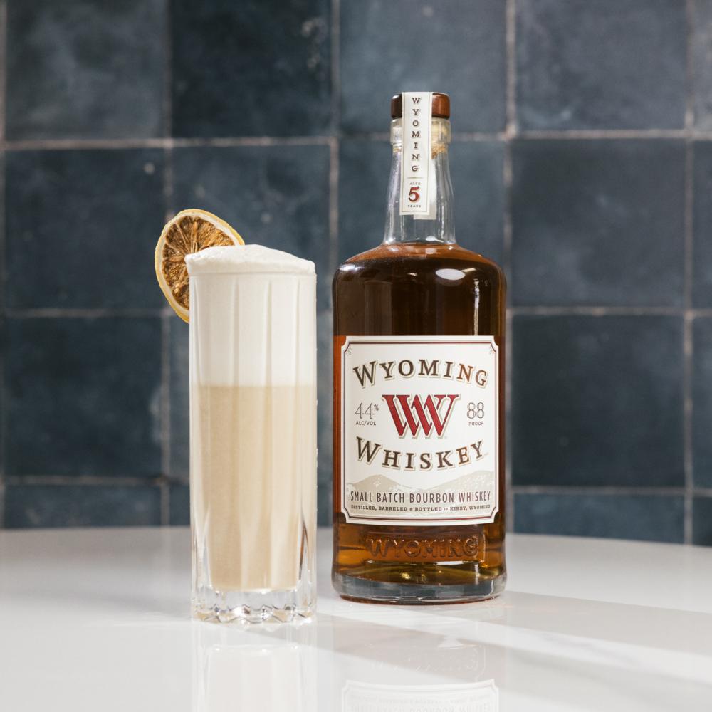 bottle of whiskey next to a tall cocktail glass